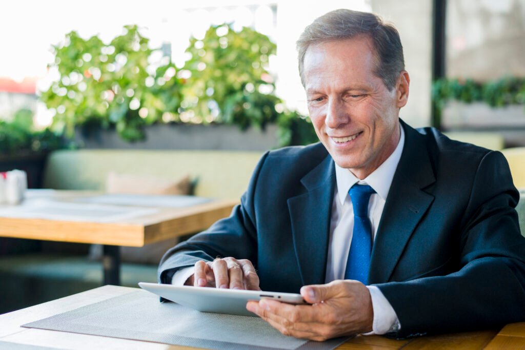 smiling mature businessman working digital tablet restaurant